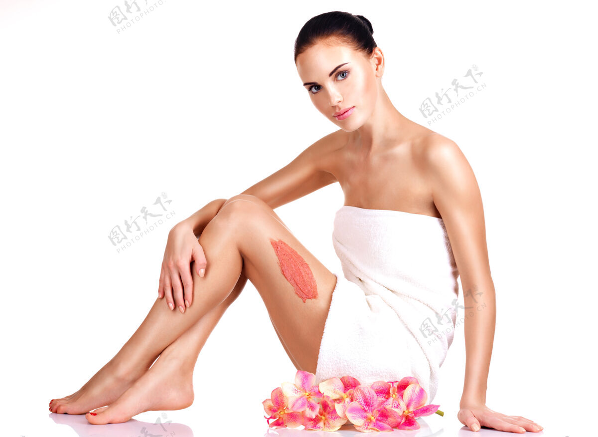 腿美丽的年轻女子用花草擦洗健康护理皮肤