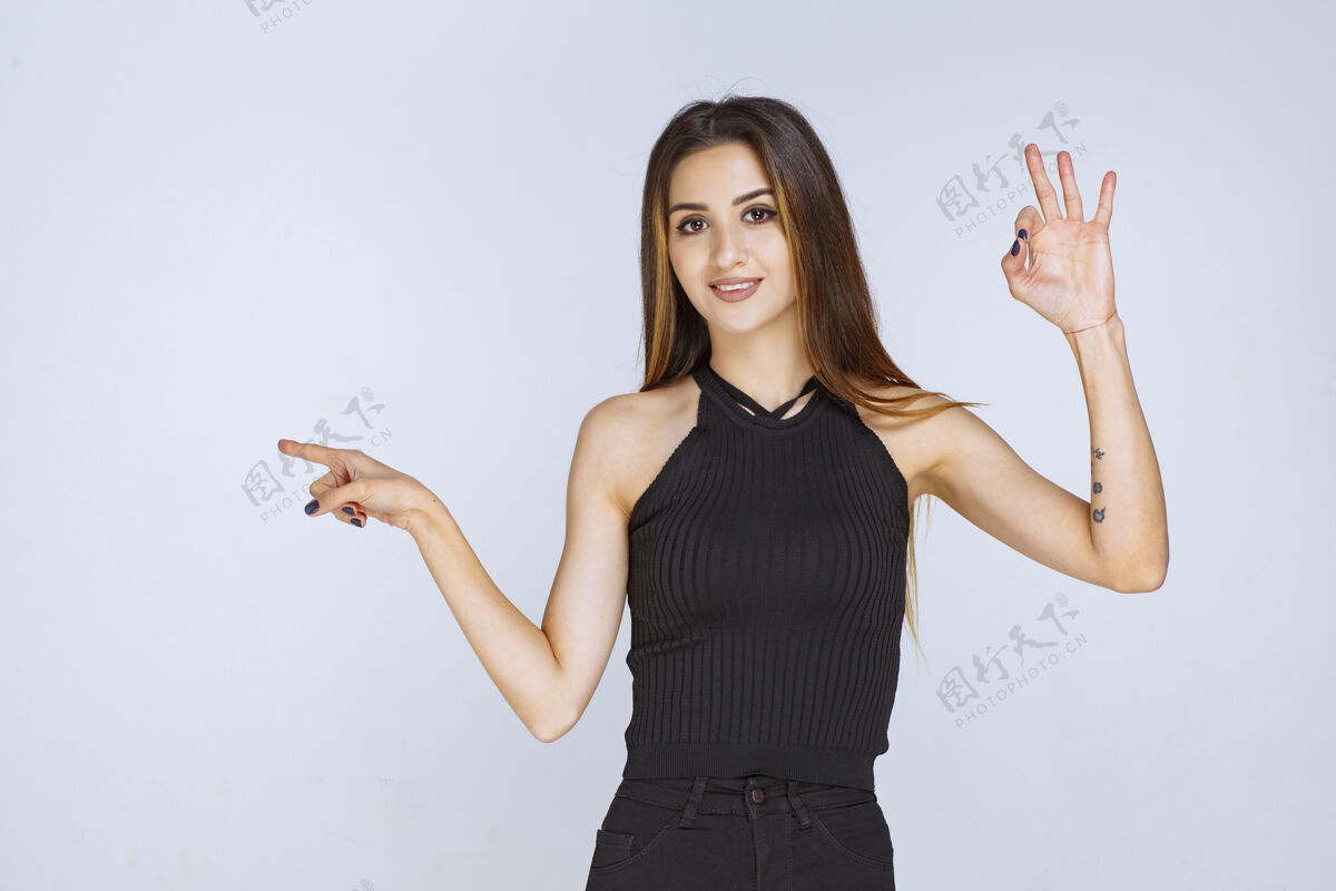 休闲穿黑衬衫的女人用手指着某处成人方向年轻人