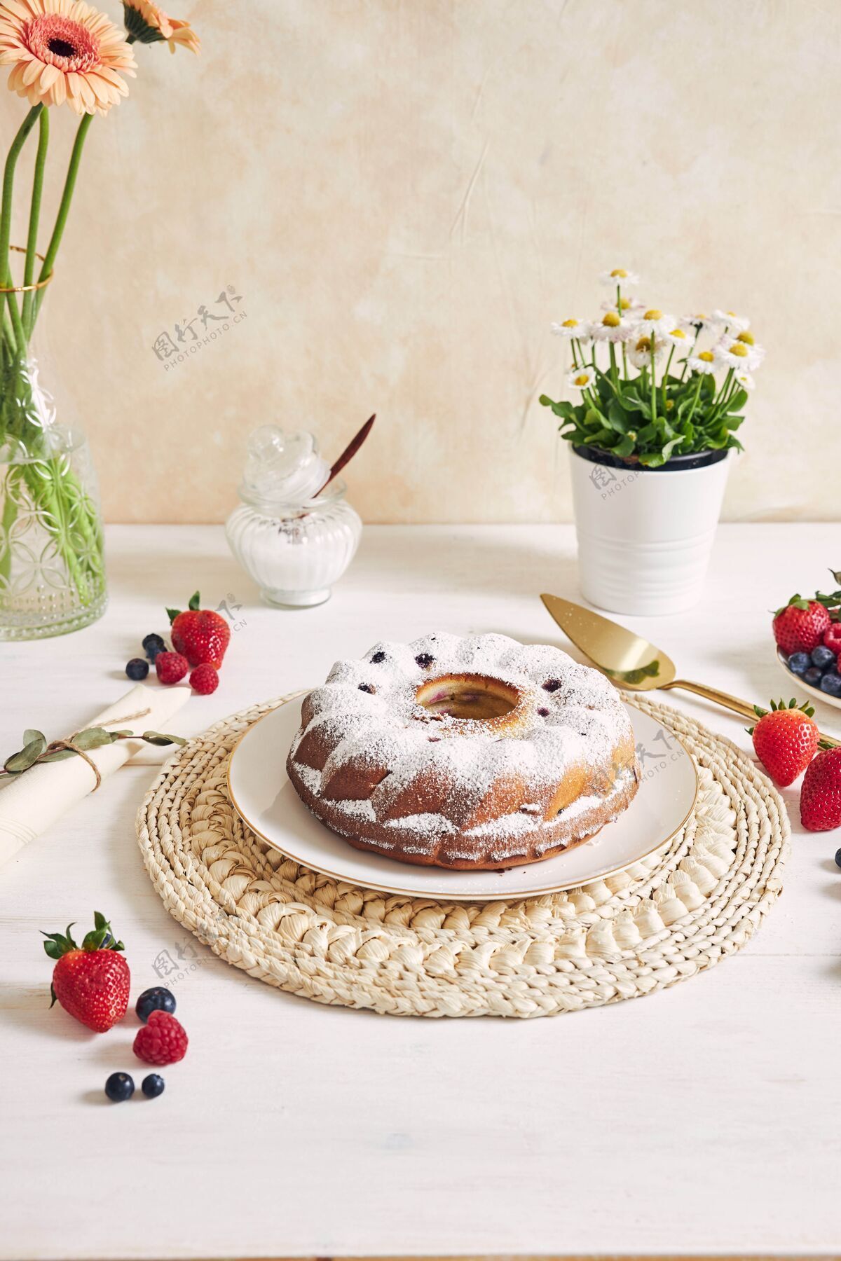 面包房一张白色的桌子上摆着水果和粉末的环形蛋糕食物美味蛋糕