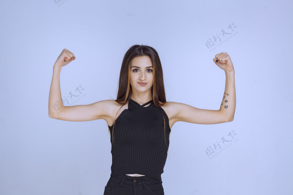 姿势一个穿着黑色衬衫的女人展示她的拳头 感觉很强大年轻积极强壮