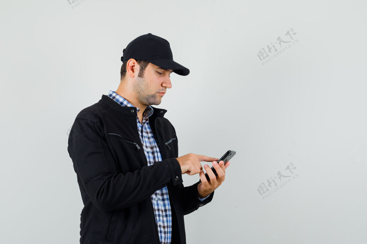 时尚年轻人用手机在衬衫 夹克 帽子和繁忙的样子 前视图自信发型手机