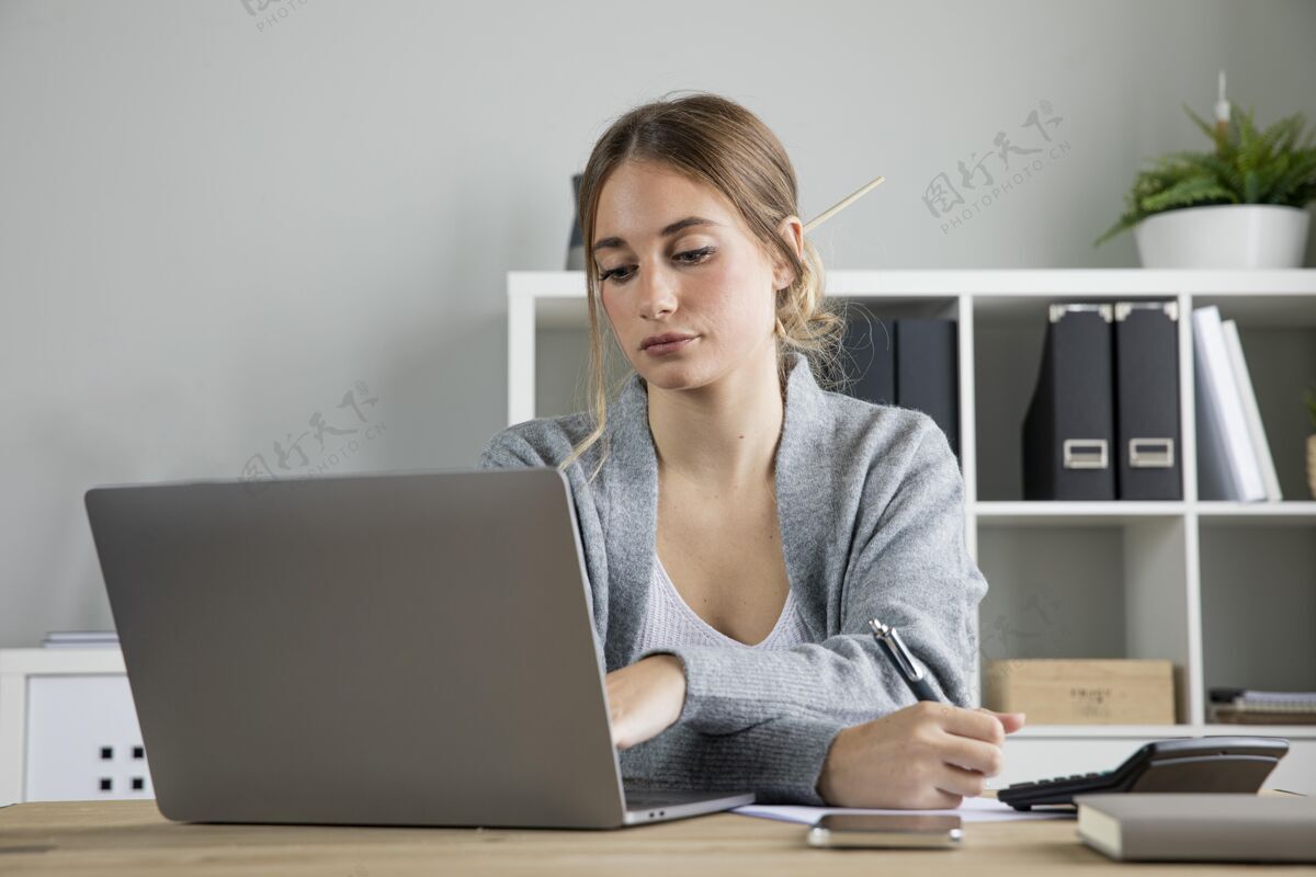 工作中等身材的女人在笔记本电脑上工作自由职业者笔记本电脑室内