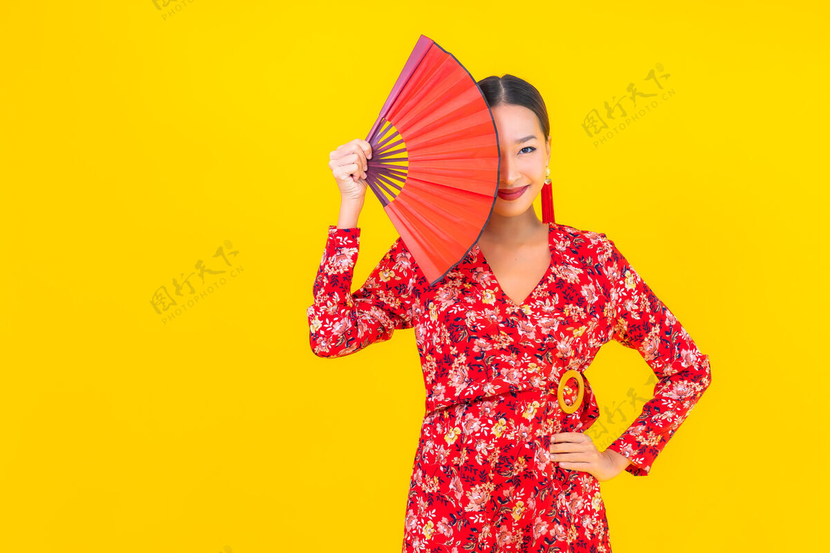 旗袍美丽的亚洲年轻女子在彩色墙上的中国新年概念中的微笑华丽女性红包