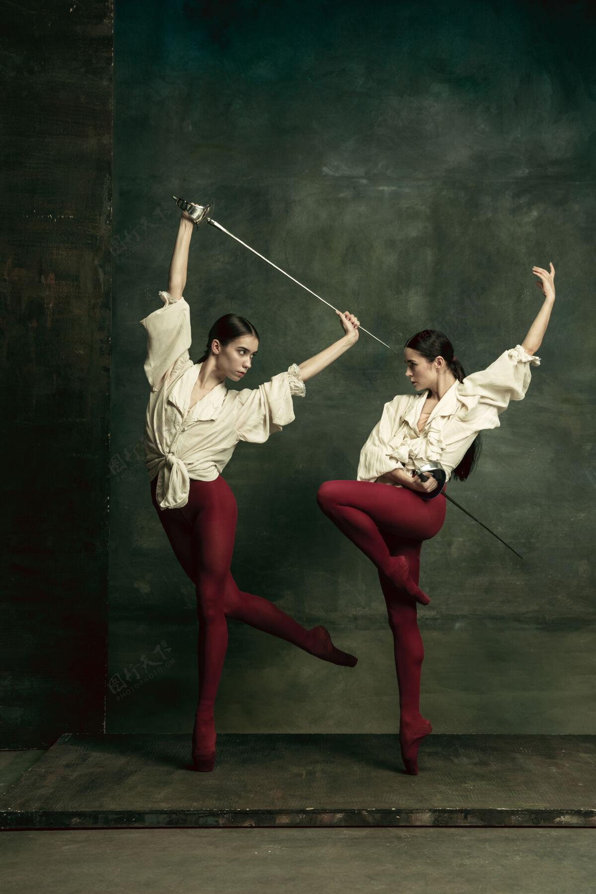 现代激情四射两个年轻的女芭蕾舞演员喜欢在深绿色的墙上拿着剑的决斗者高加索模特们一起跳舞芭蕾舞和当代舞蹈概念芭蕾舞明亮训练