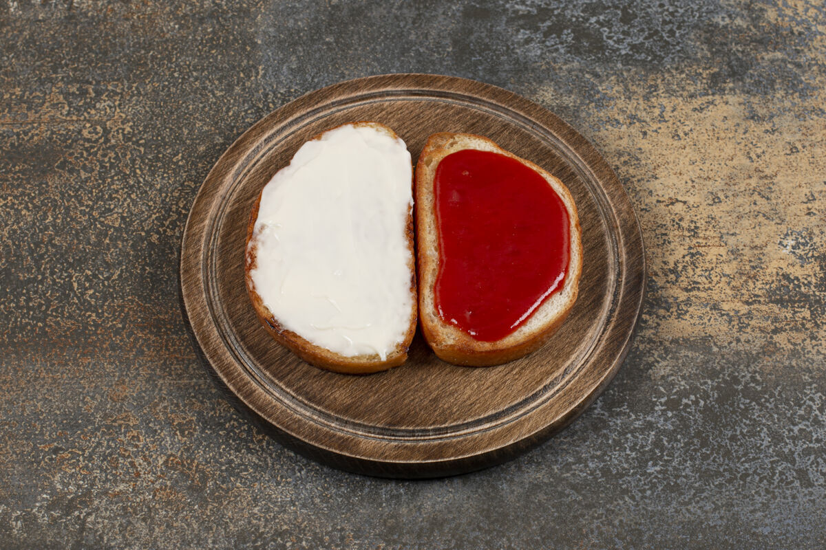 切片在木板上烤草莓酱和酸奶油餐吐司面包