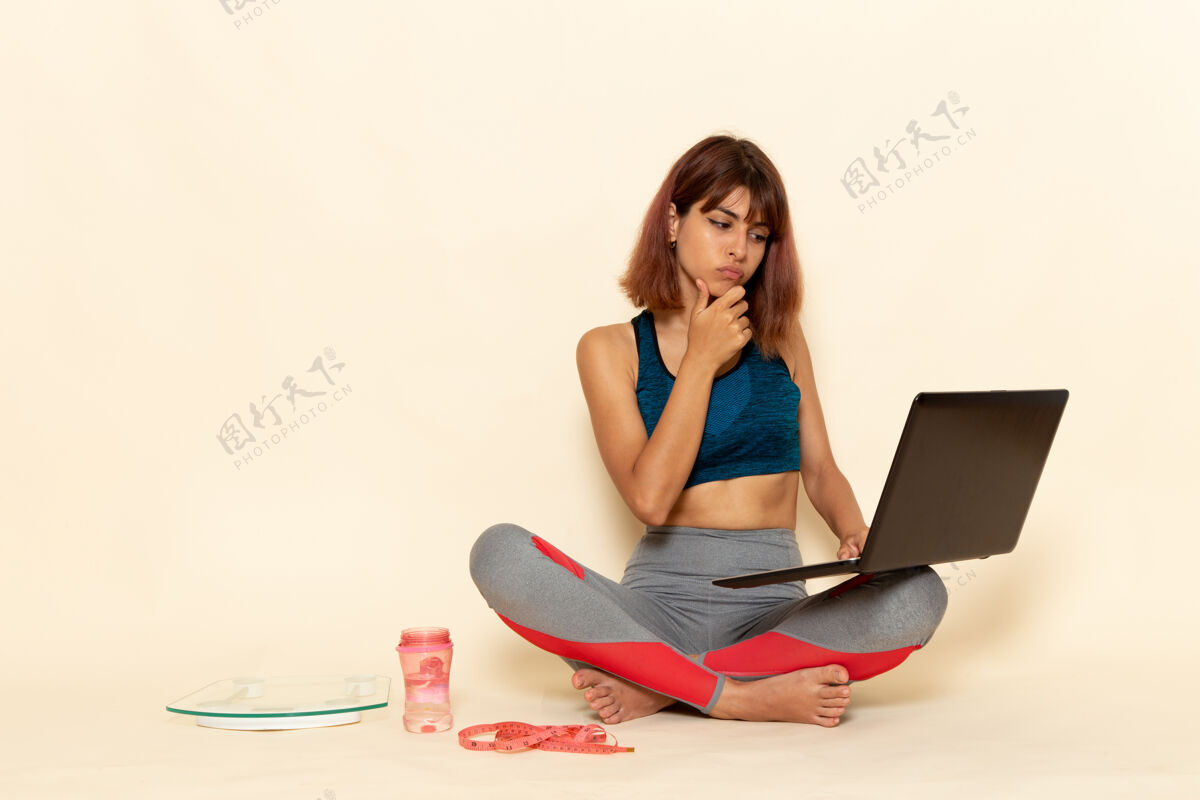 衬衫年轻女性穿着蓝色衬衫 在浅白的墙上使用笔记本电脑 身体健康笔记本电脑快乐锻炼