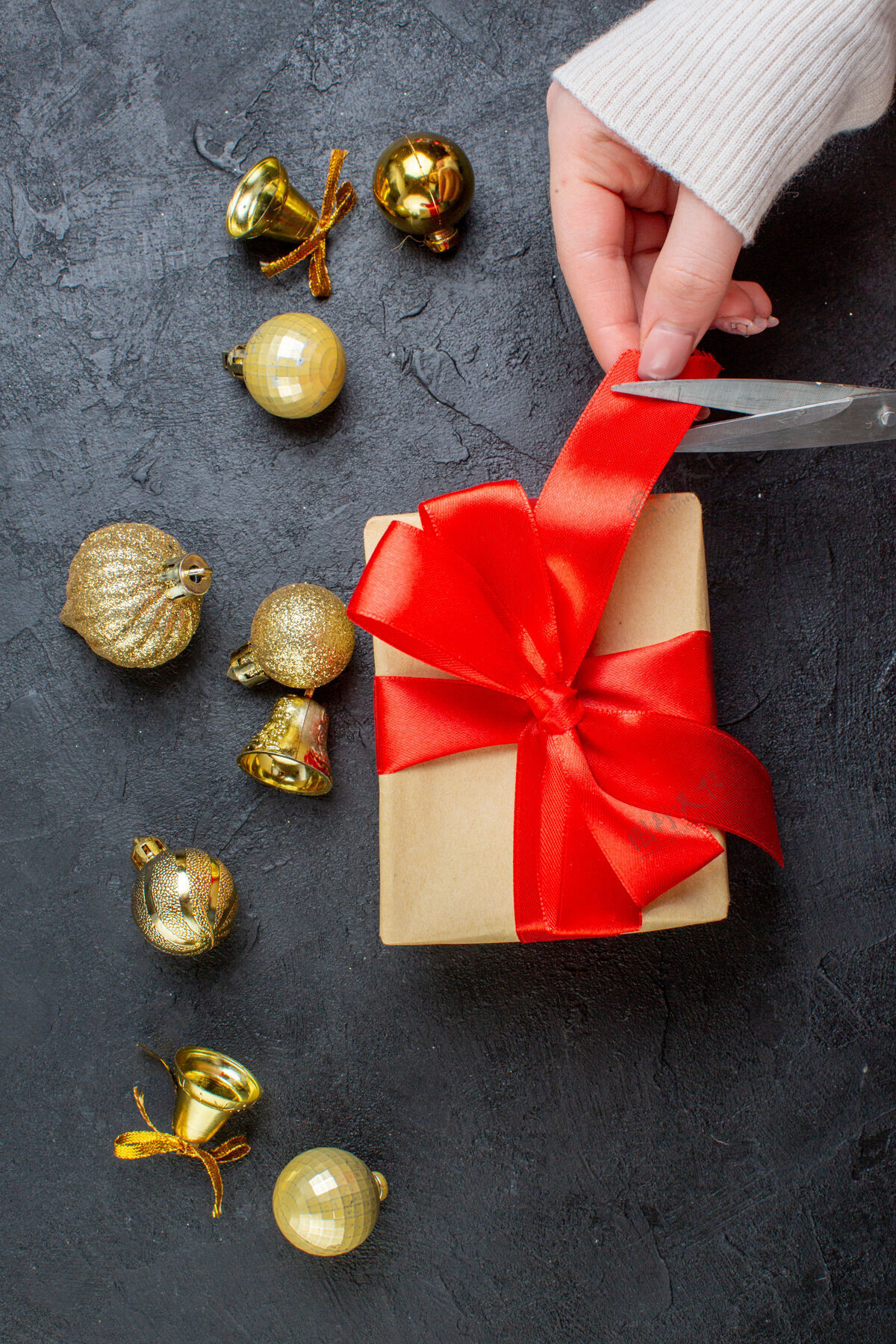 圣诞节礼品盒上手工切割的红丝带和深色背景上的装饰配件的垂直视图头发幻灯片剪辑削减