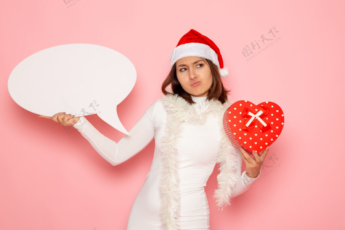 肖像正面图年轻女子手持白色大招牌 在粉色墙壁上呈现情感色彩的雪花圣诞新年假期雪颜色情感