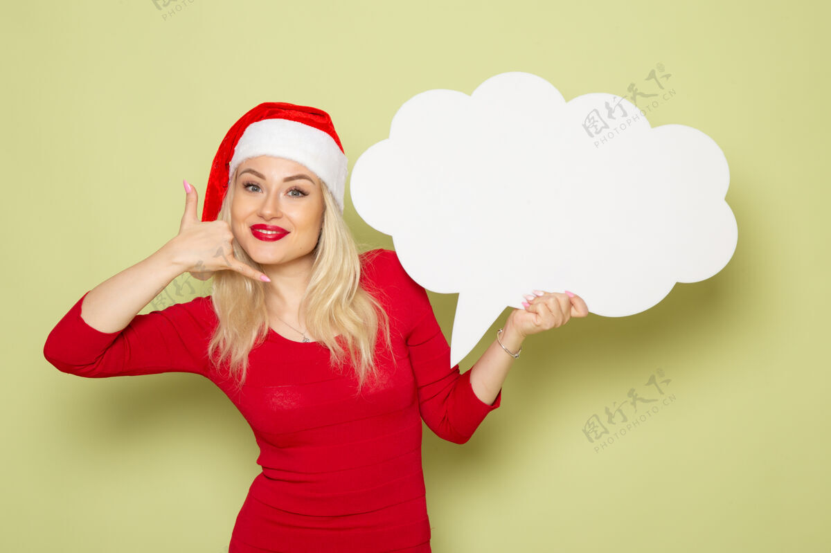 美丽的女性正面图美丽的女性手持云形白色标志在绿色墙上圣诞雪照片节日情绪新年形状美丽肖像