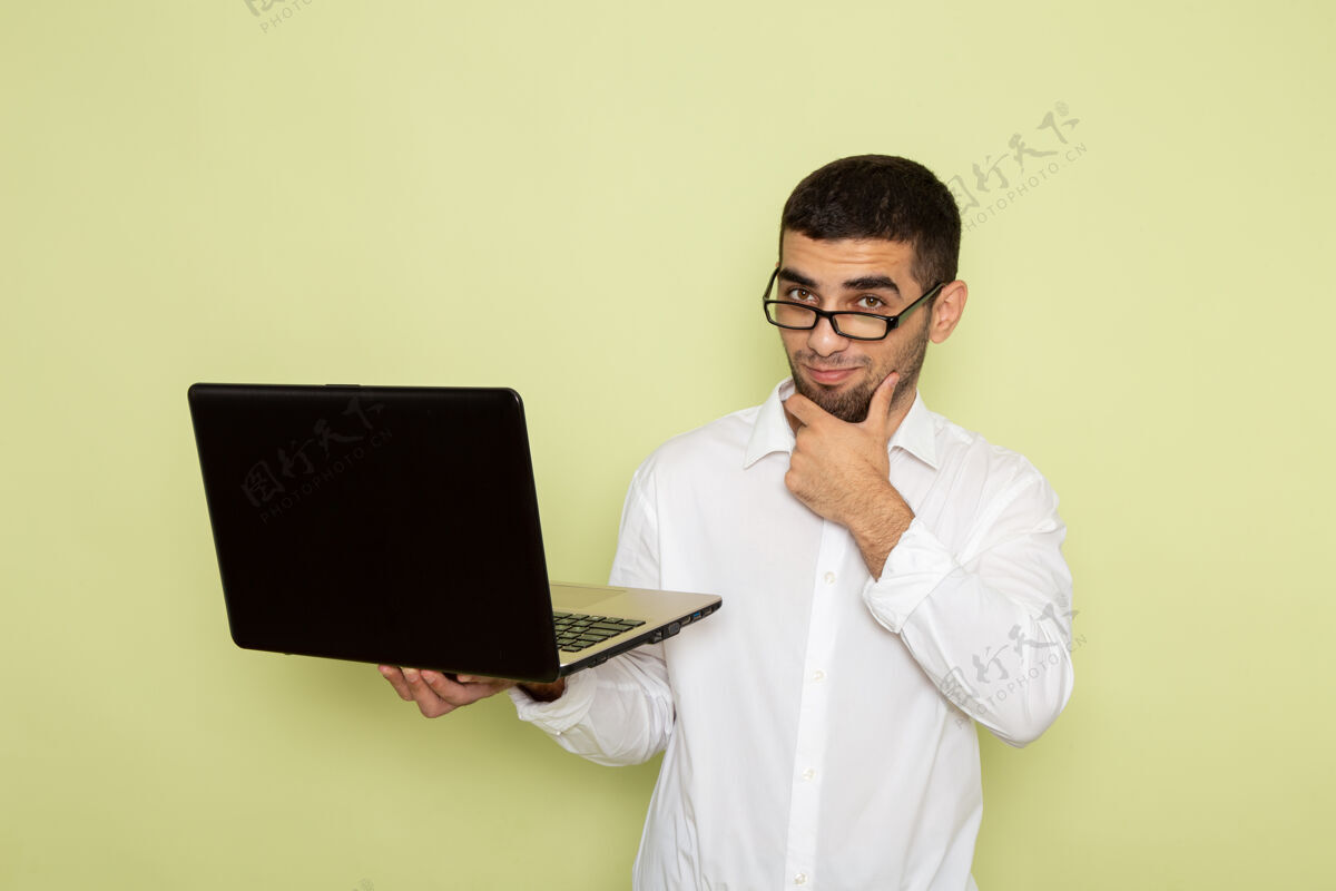 商务男士身穿白衬衫的男办公室工作人员手持和使用笔记本电脑在浅绿色墙上思考男士男士工作