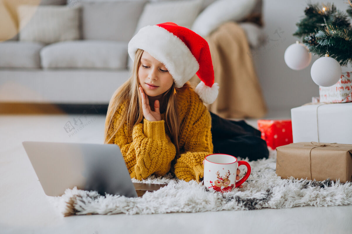 圣诞树可爱的女孩在圣诞树旁用电脑时尚可可在家度假
