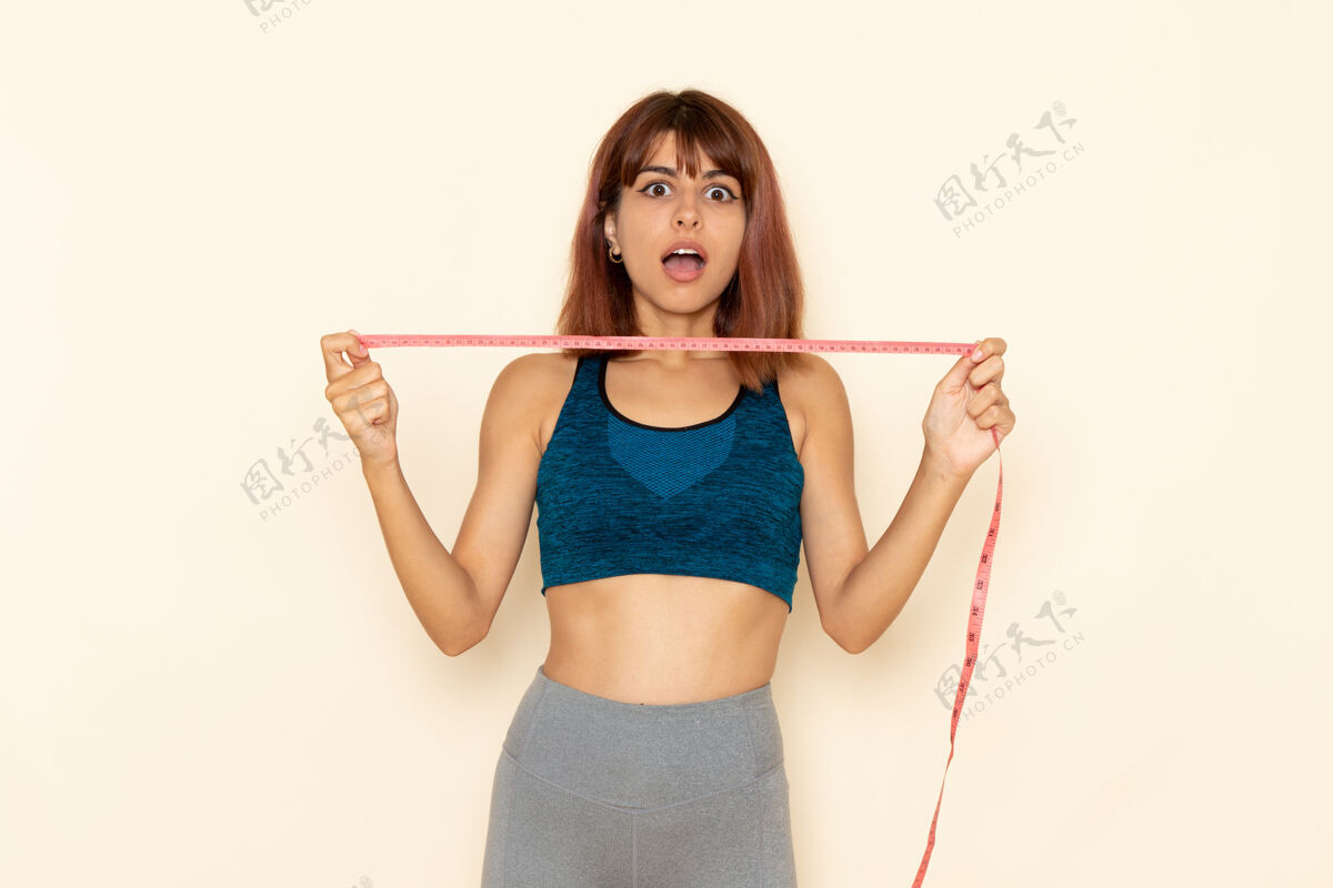 女性年轻女性的前视图 穿着蓝色衬衫 身体健康 在浅白的墙上测量她的腰围前面衬衫锻炼