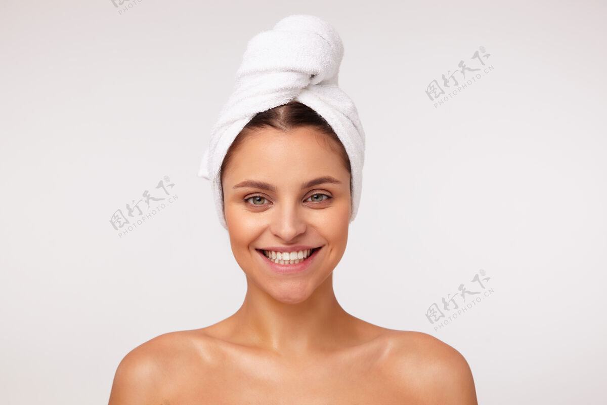 绿色快乐的年轻漂亮的黑发女士的肖像显示她完美的白色牙齿 微笑广泛 在白色的背景与裸体肩膀摆姿势头发白色欢呼