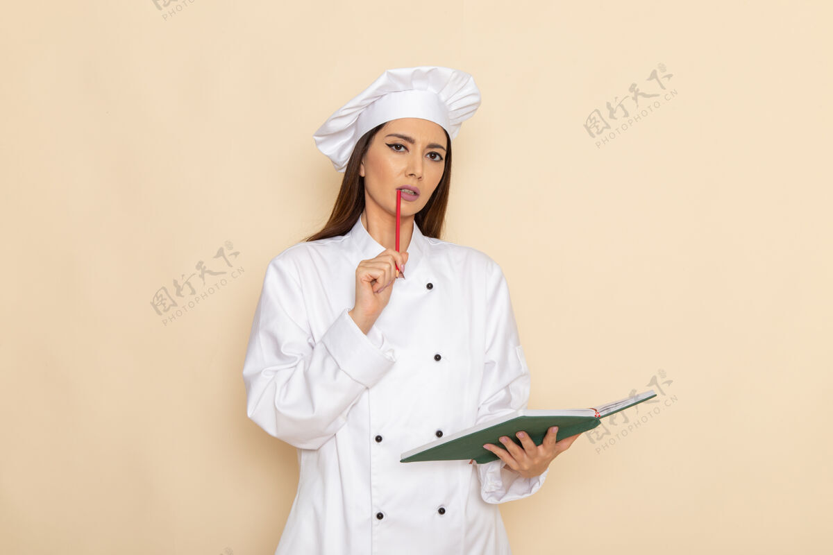 正面身穿白色厨师服的年轻女厨师手持抄写本 在浅白的墙上思考工作厨房女性