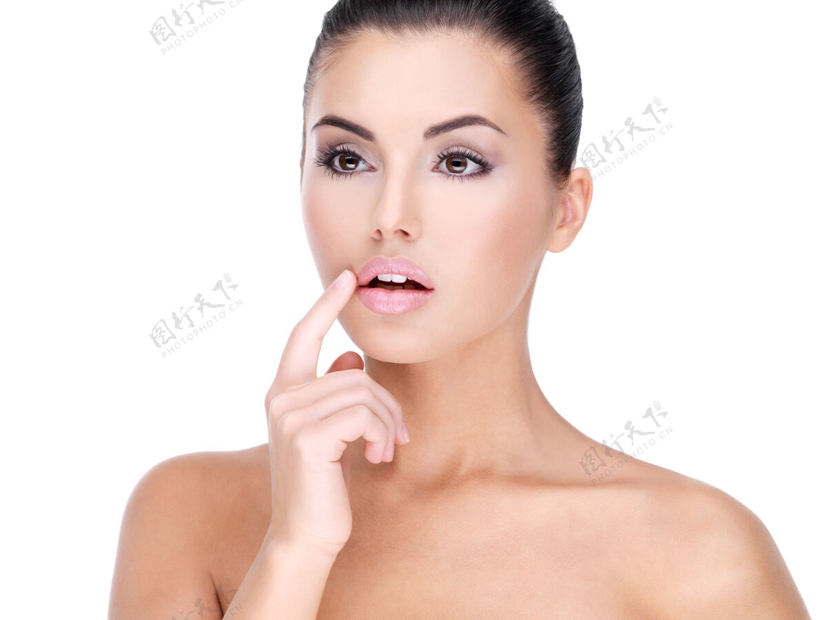 女人一张漂亮的年轻女子的脸 手指放在嘴唇上-在白墙上女性特写手指
