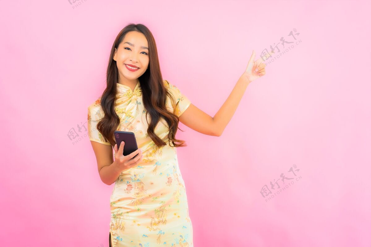 手机在粉红色的墙上画一幅美丽的亚洲年轻女子手持智能手机的画像电话女人肖像