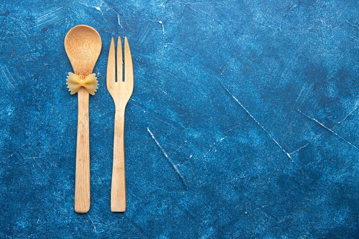 法法法勒顶视图木制叉子勺farfalle在勺子上蓝色的桌子与自由空间套装厨房叉子