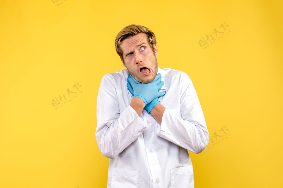 微笑正面图年轻的男医生正把自己塞进黄色背景的医学病毒大流行中前面观点男性