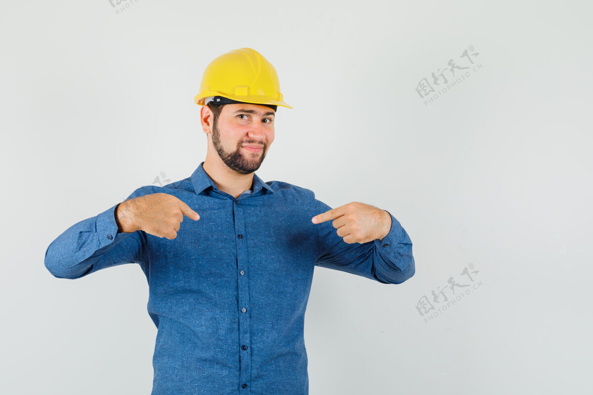 头脑风暴年轻的工人指着自己的衬衫 头盔 看起来很自豪工业谈话指向