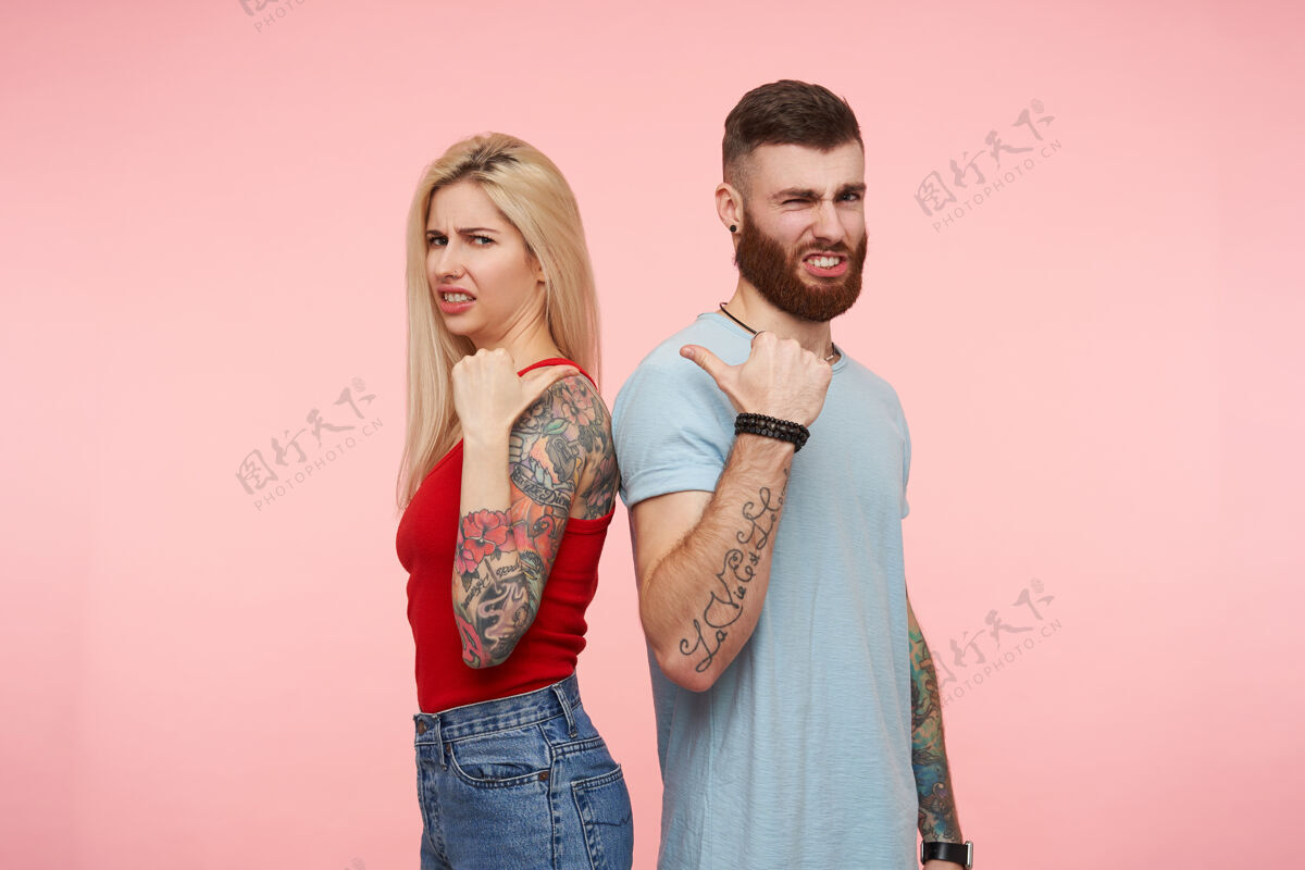 展示不高兴的年轻漂亮纹身的人举手 愁眉不展的脸上显示对方 孤立的粉红色拇指摆姿势黑发