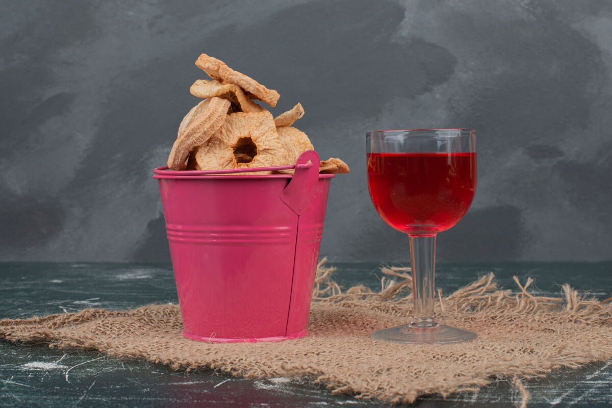 篮子粉红色的篮子里放着干果和果汁 放在大理石墙上饮料干果食品