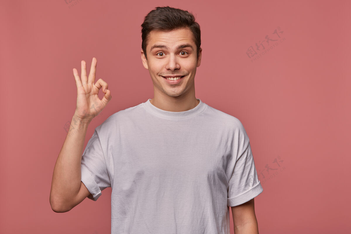 表情一个年轻开朗的人的肖像 穿着一件空白的t恤 摆出一副很好的姿势 站在粉红色的椅子上 面带微笑男人英俊学生