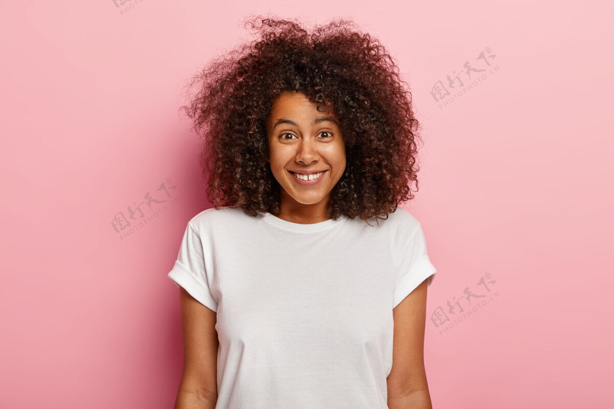 年轻可爱的美国黑人年轻女子的特写肖像正面微笑 享受有趣的场景 被逗乐 笑笑话 深色卷发 穿着休闲装积极真诚理发