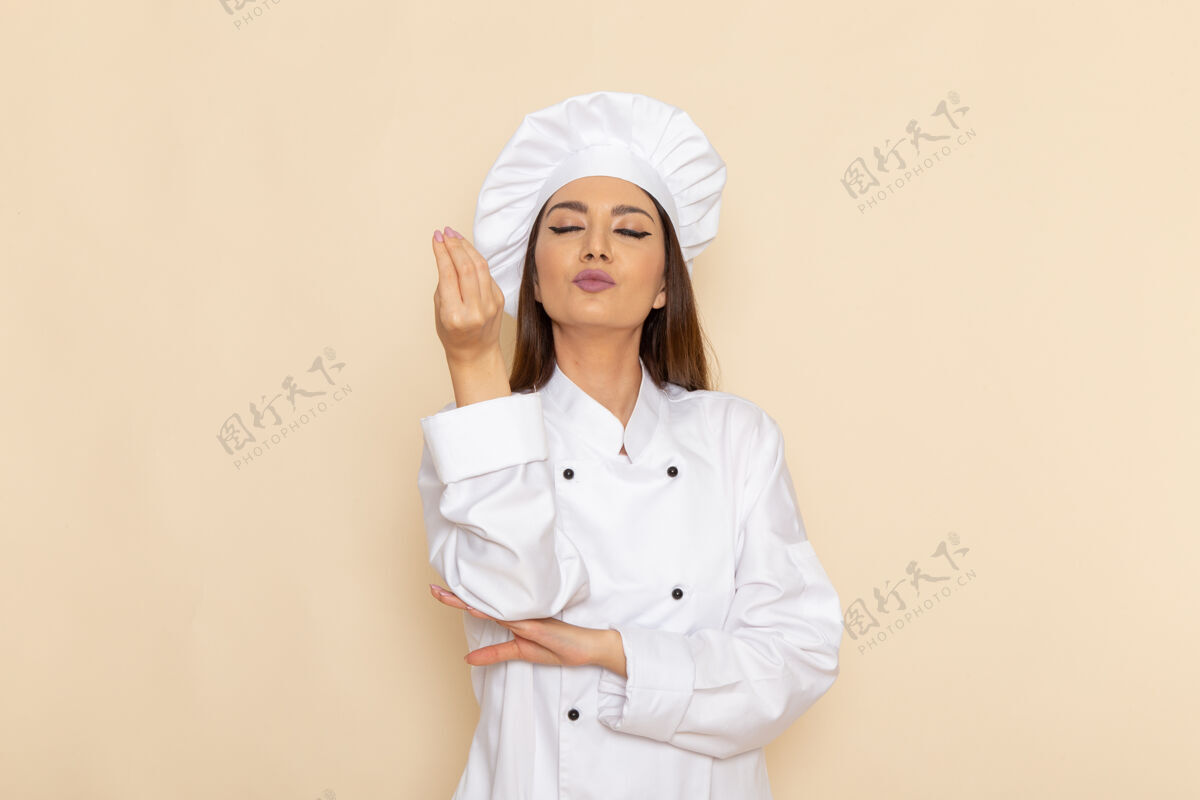 工作白色墙壁上穿着白色厨师服的年轻女厨师的正视图膳食外套实验室外套