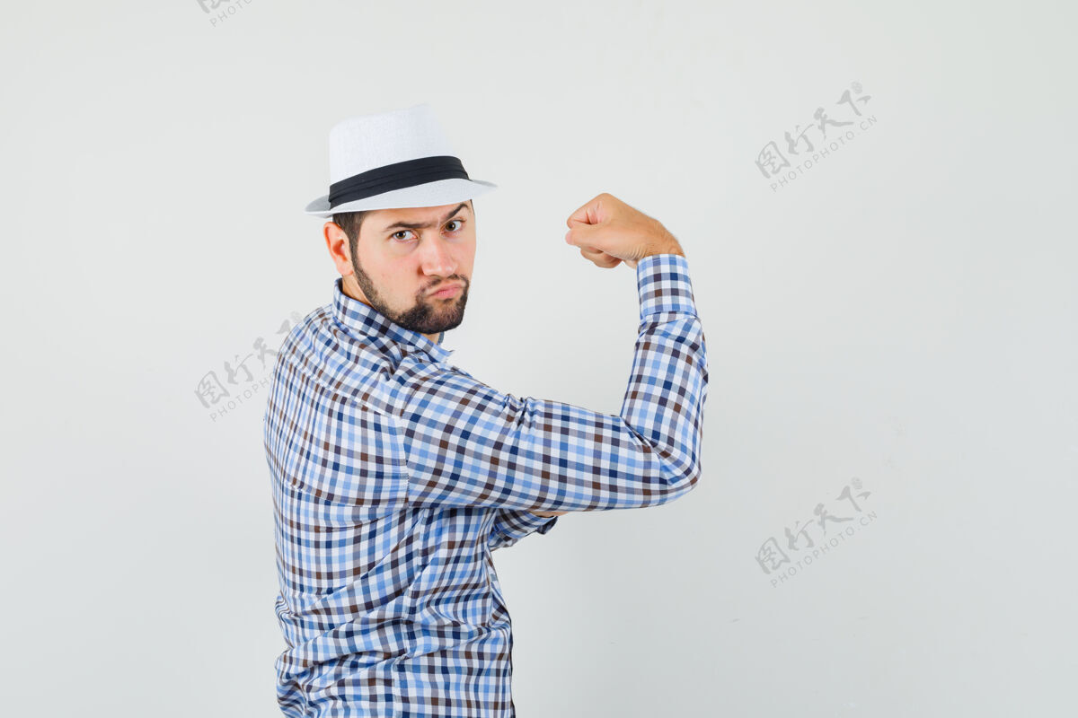 男性年轻人穿着格子衬衫 戴着帽子 露出胳膊上的肌肉 看上去很坚决自信胡须决议