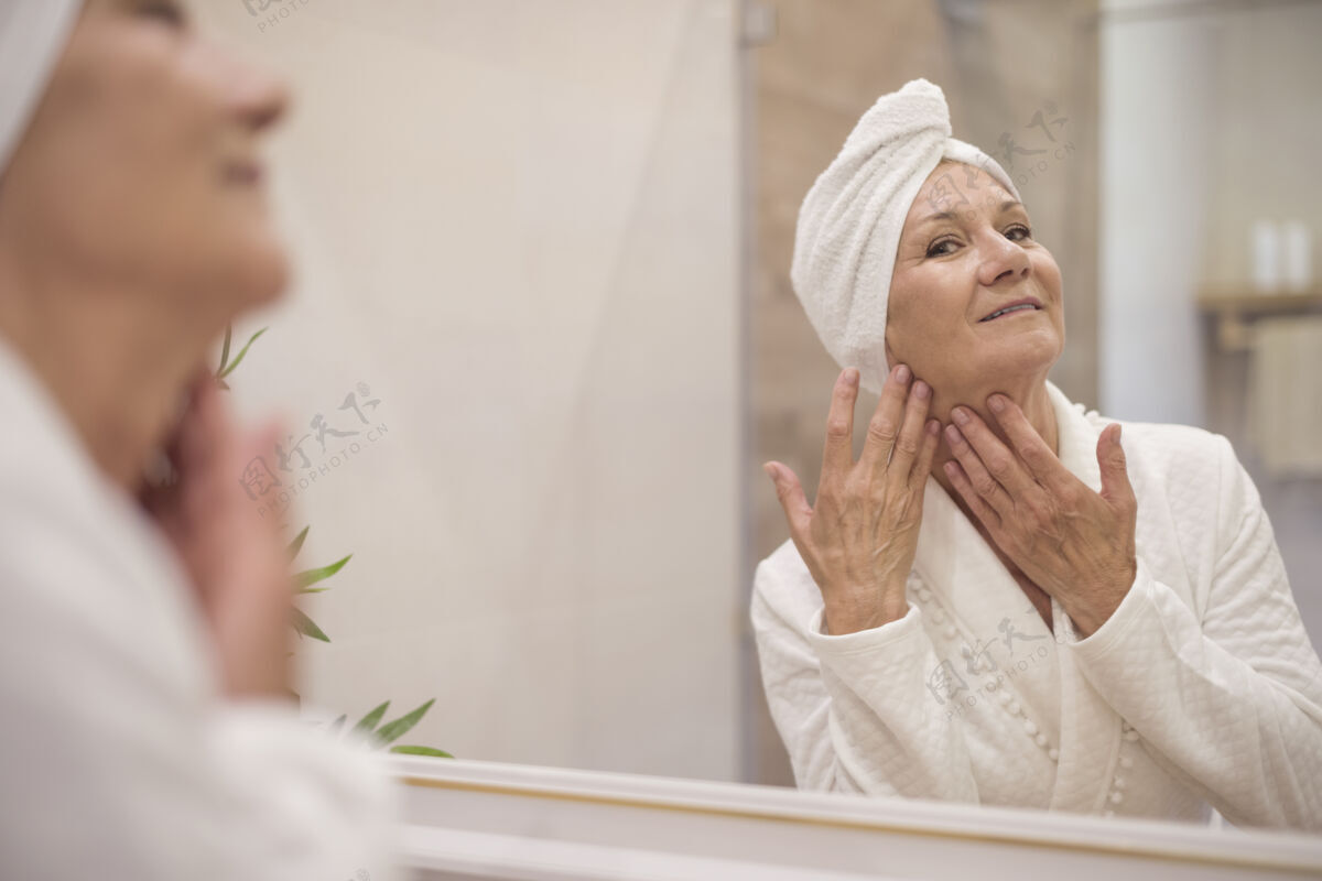 皮肤漂亮的老太太在镜子里浏览精心打扮浴袍人类皮肤