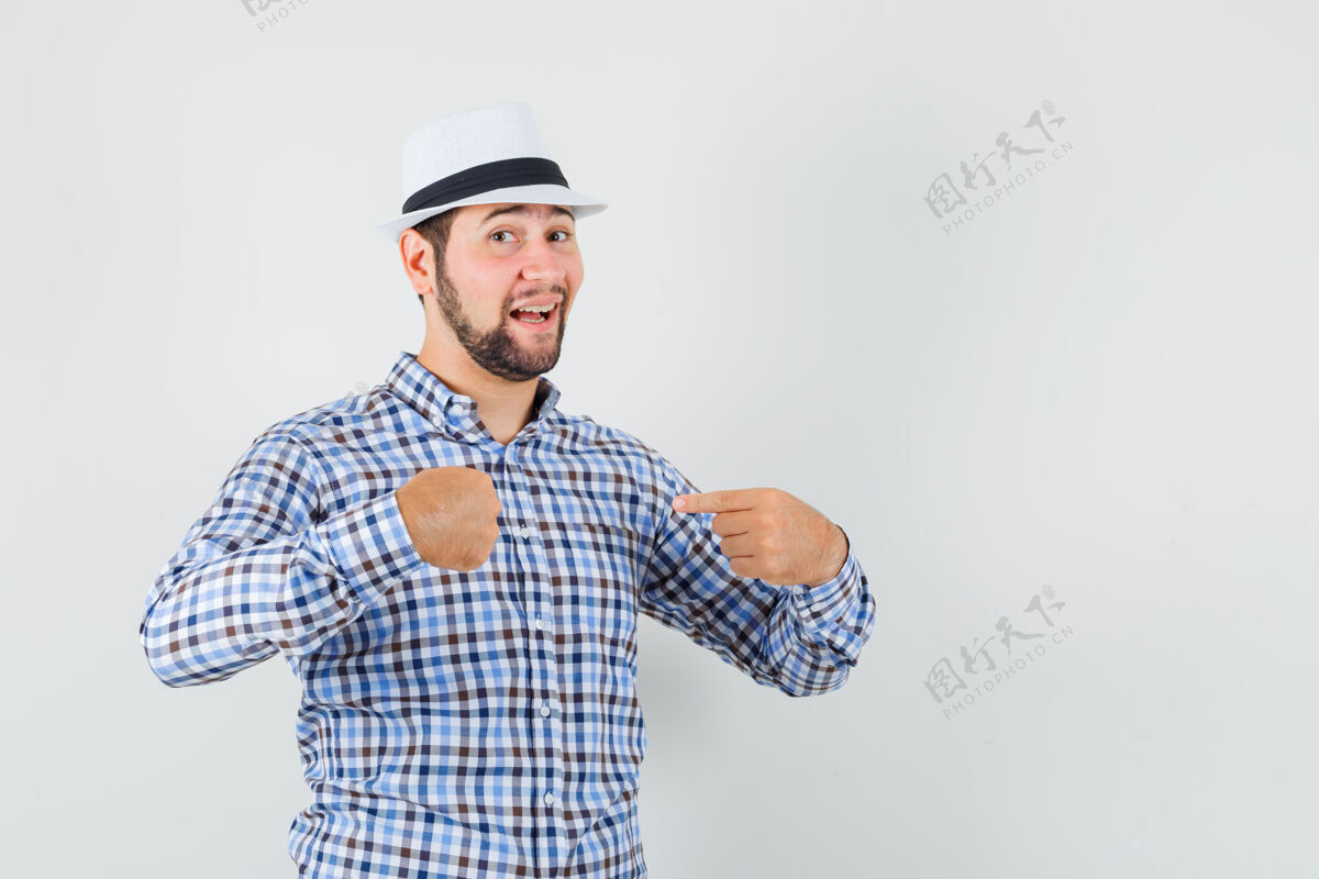 表情穿着格子衬衫 戴着帽子的年轻男子指着自己 看上去很自豪 正对着前方站立办公室虚拟