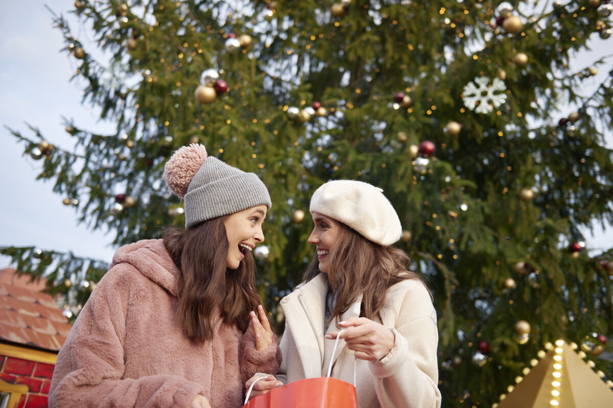 消费主义两个女人和一棵巨大的圣诞树温暖面对面朋友