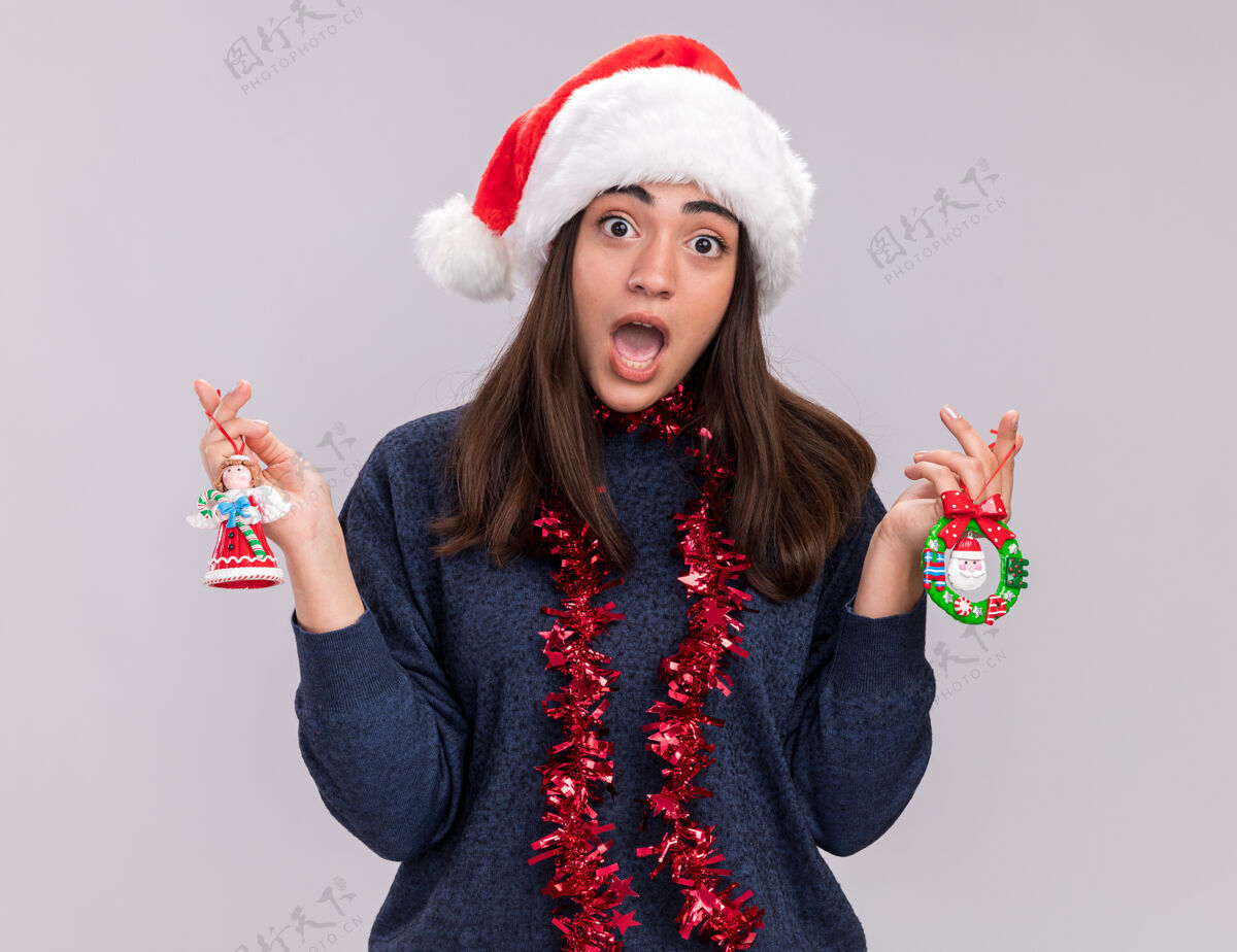 焦虑焦虑的白人女孩戴着圣诞帽 脖子上戴着花环 手里拿着圣诞树玩具空间新快乐
