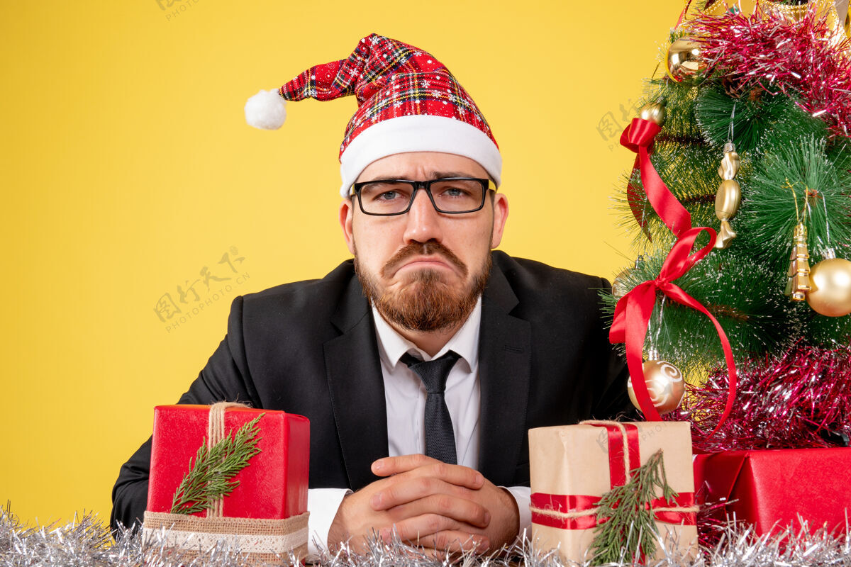 近前面近距离看 男工人围坐在礼物和小树周围 黄色的脸上挂着悲伤的表情年工人坐
