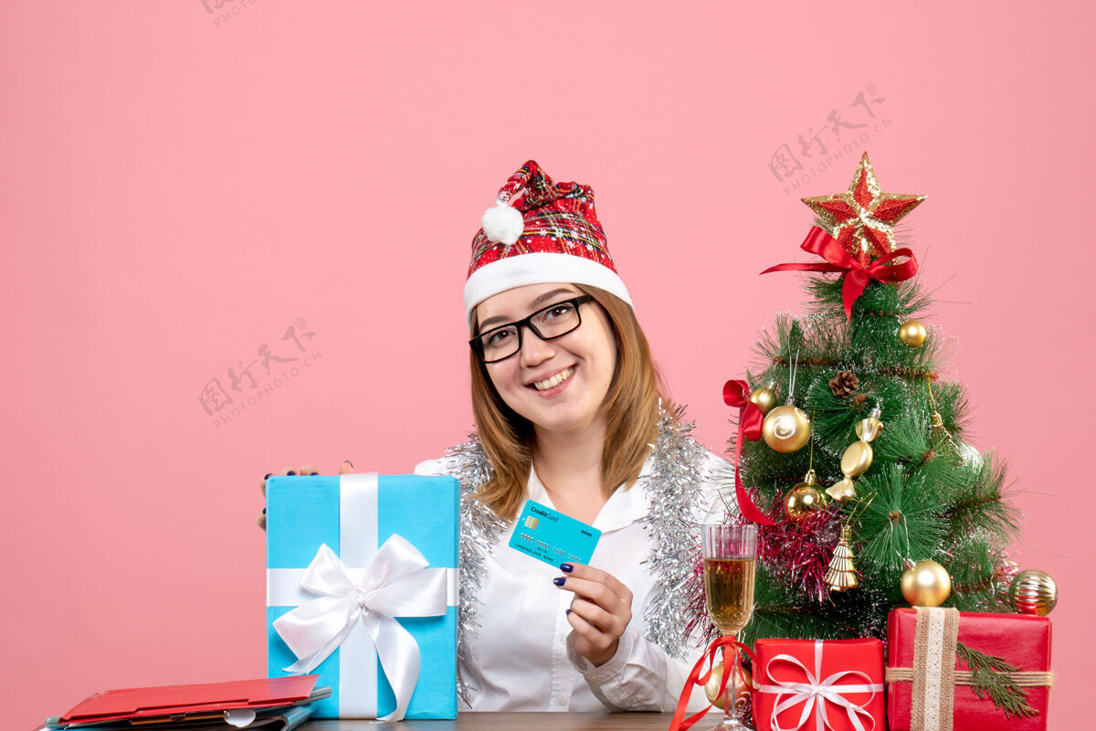 抱着女工坐在粉红色的椅子上拿着银行卡的正面图女工粉色圣诞节