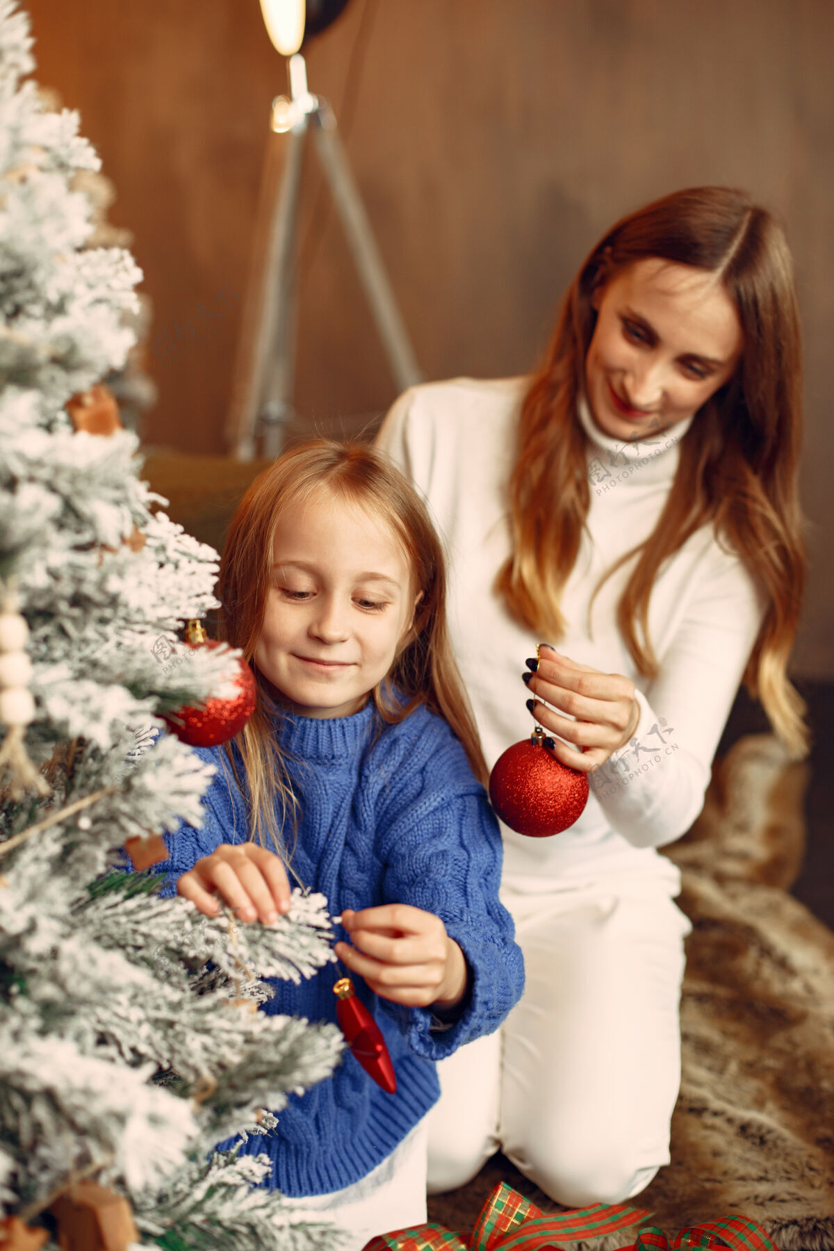 杉木人们在为圣诞节做准备母亲在和女儿玩耍一家人在节日的房间里休息孩子穿着蓝色毛衣装饰女性发光