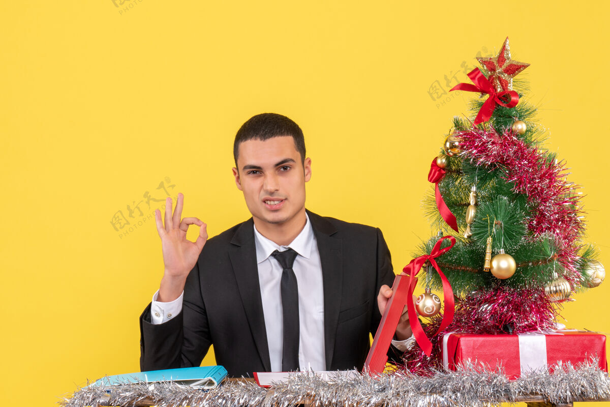 商人正面图西装革履的男人坐在桌子旁 手里拿着文件 准备着圣诞树和礼物礼物桌子文件