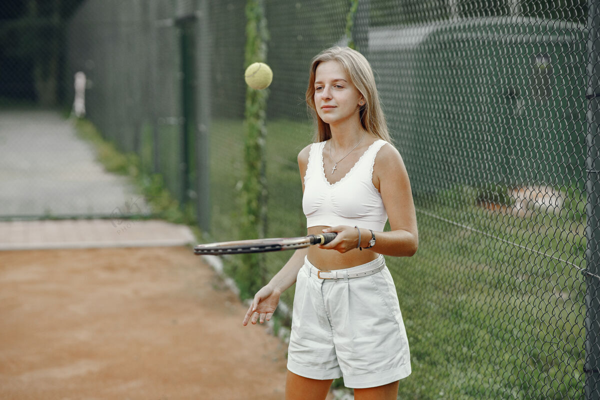 人今天玩得很开心 穿着t恤的年轻女子拿着网球拍和球的女子竞技活动专注