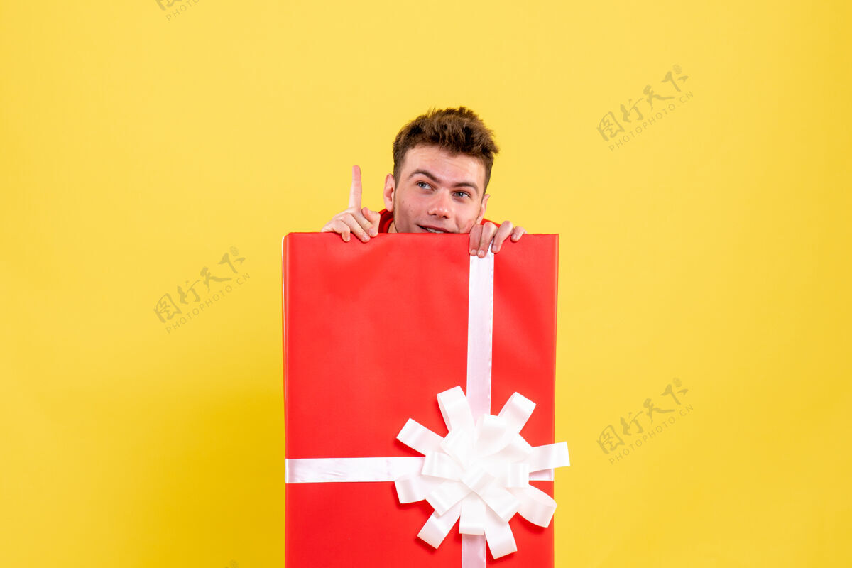 年轻男性正面图年轻男子藏在礼品盒内圣诞节颜色里面