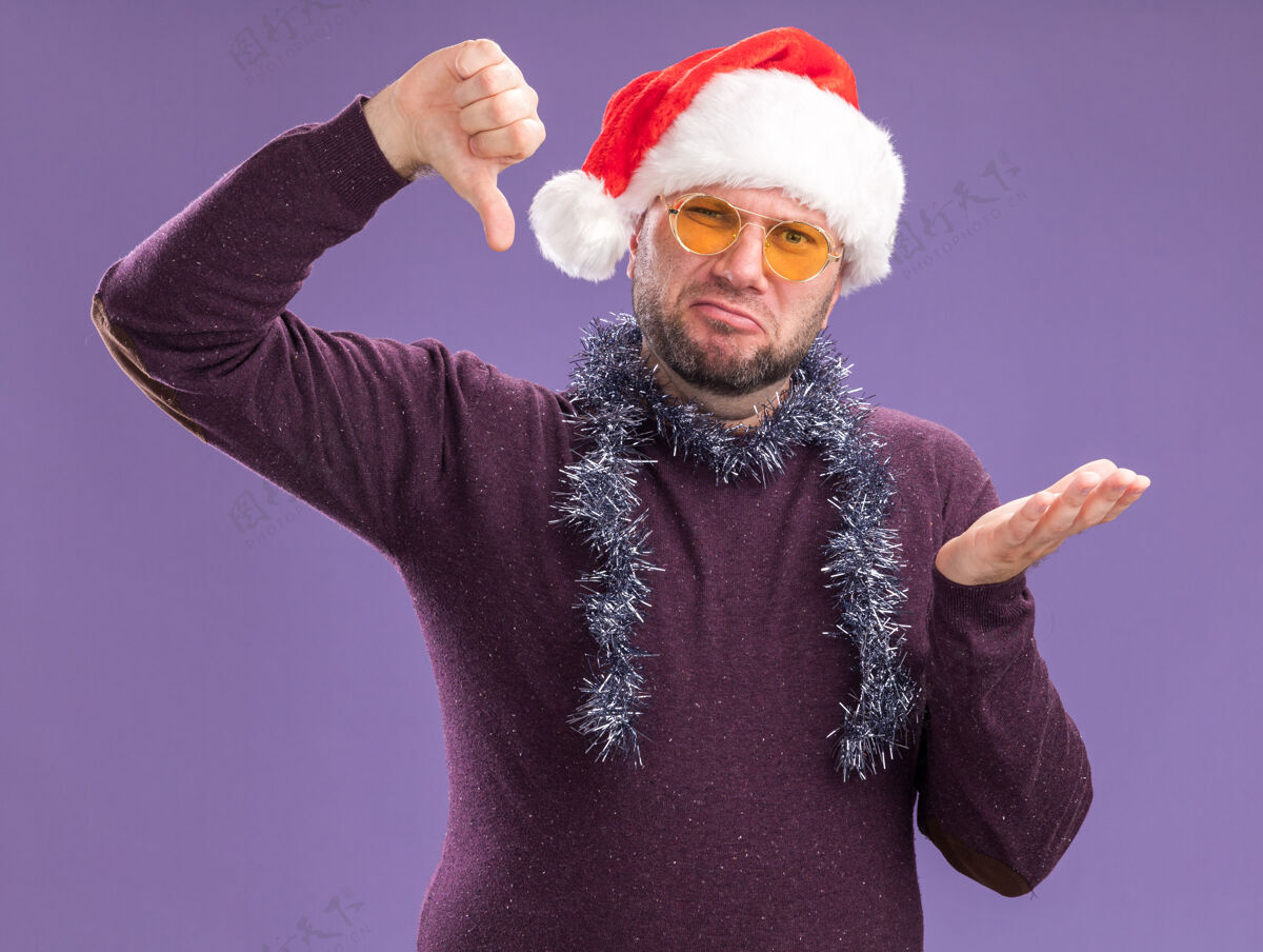 帽子一个戴着圣诞帽 脖子上戴着金箔花环 戴着眼镜的中年男子 双手空空 拇指朝下 孤零零地躺在紫色的墙上金属片花环空