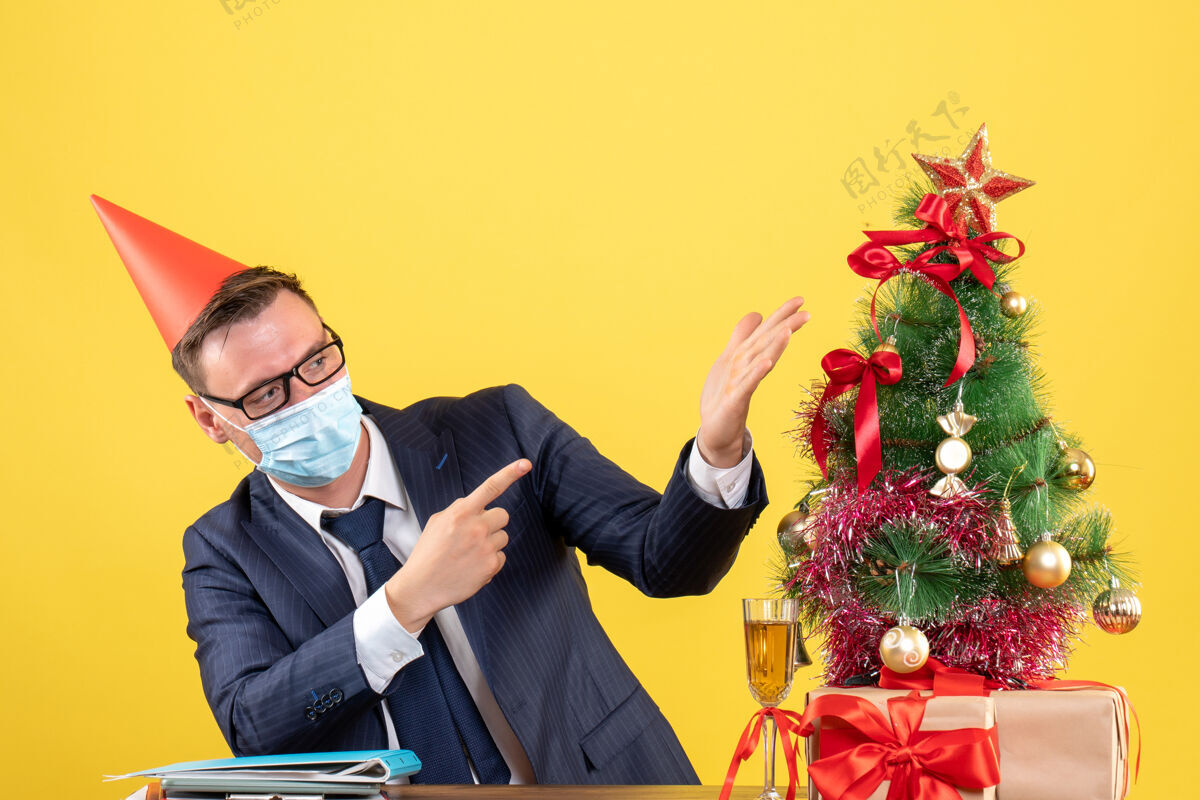 树前视图的商人与医疗面具指向圣诞树和黄色的礼物黄色圣诞节商人