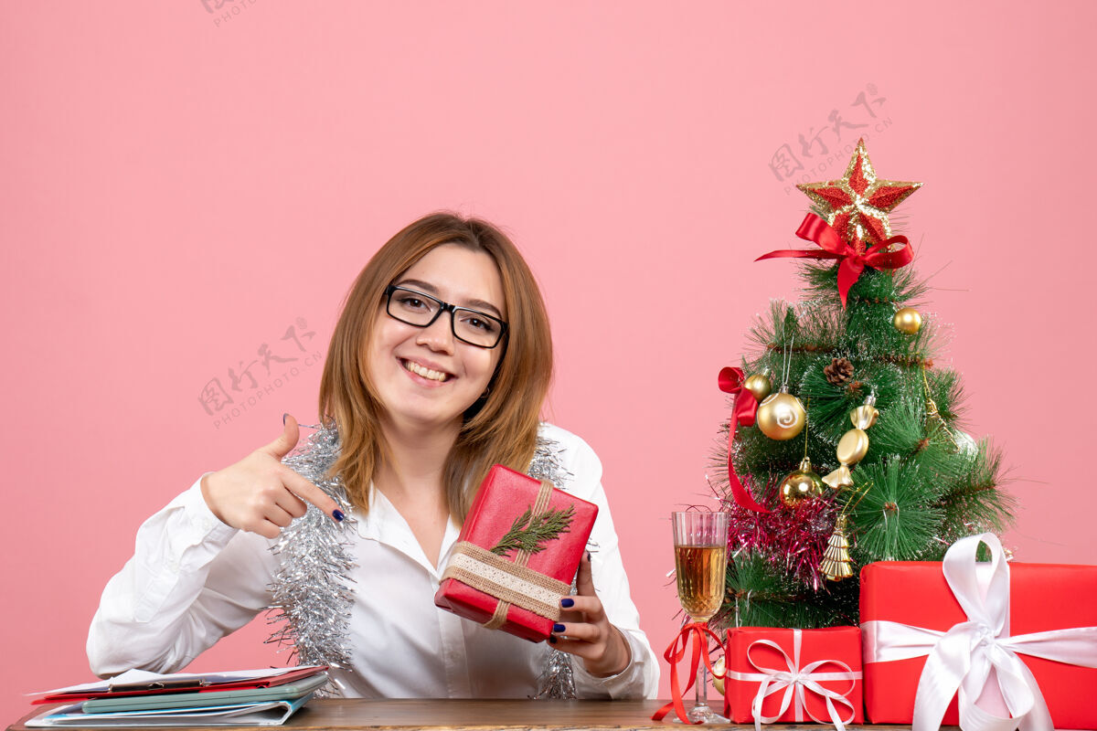 肖像女工围坐在粉红色的圣诞礼物和圣诞树旁的正视图办公室成人女工人