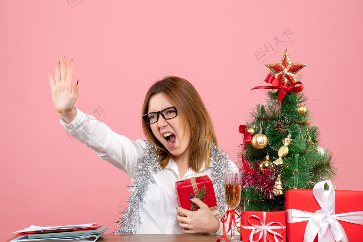 坐着女工正坐在粉红色的椅子上 手里拿着圣诞礼物工作圣诞节女工