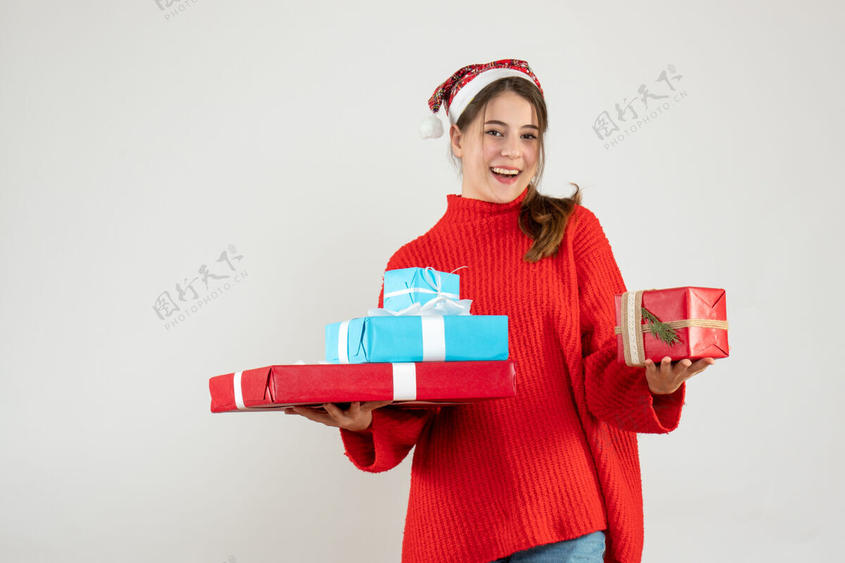 手戴着圣诞帽的快乐女孩双手捧着圣诞礼物 白色的礼物帽子圣诞老人