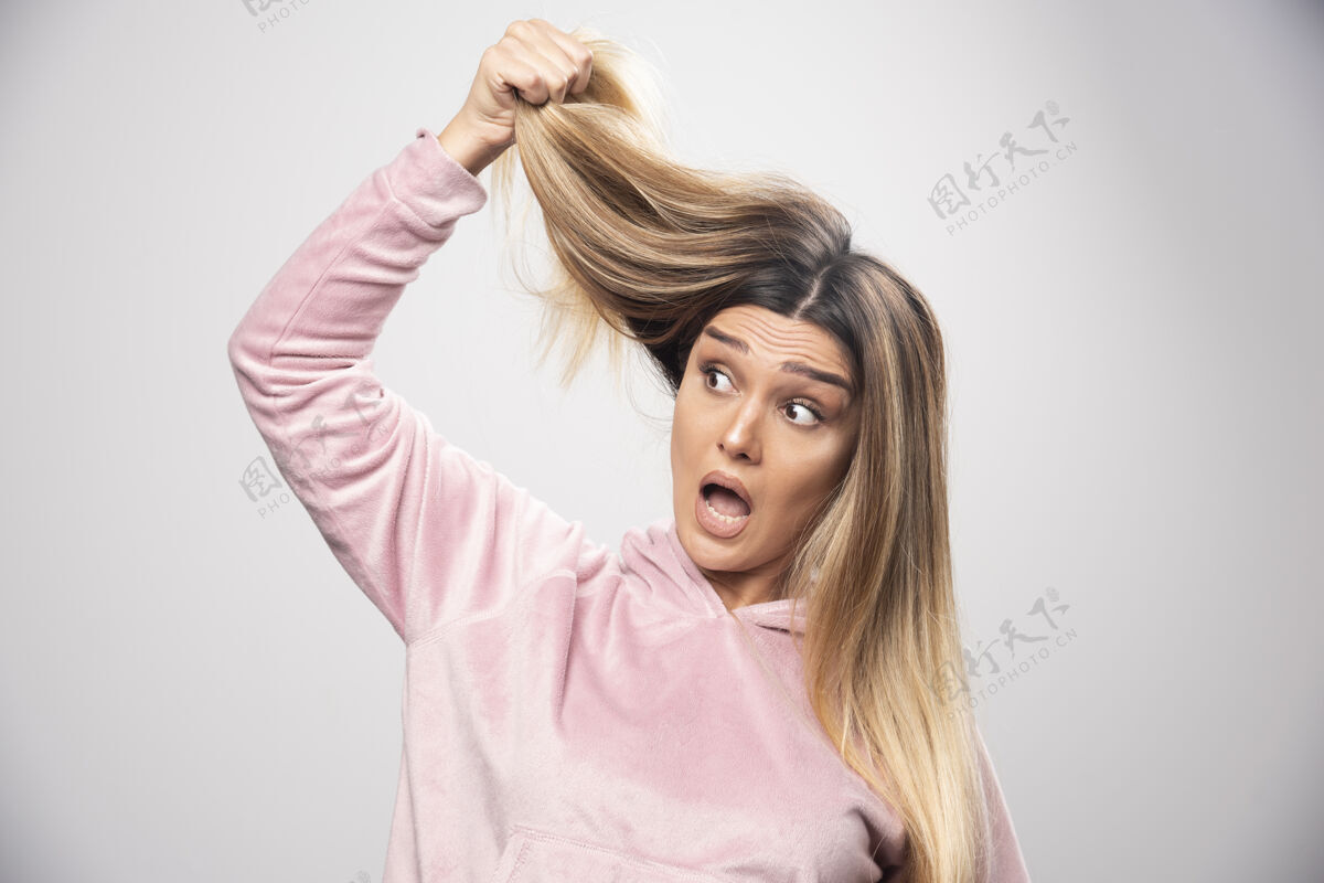 头发穿着粉色运动衫的金发女士对自己的干枯头发或发色感到不满意年轻人成年人护发用品
