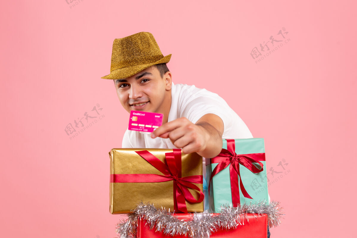 人年轻人在圣诞节前后的正面图 粉红色的墙上挂着一张银行卡圣诞节日庆祝