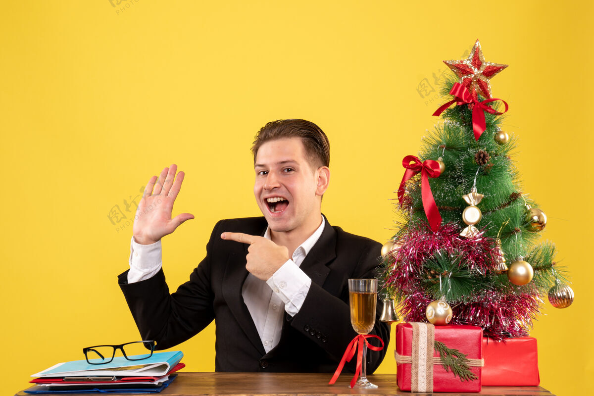 圣诞前视图年轻的男工人坐在圣诞礼物和圣诞树年份礼物男