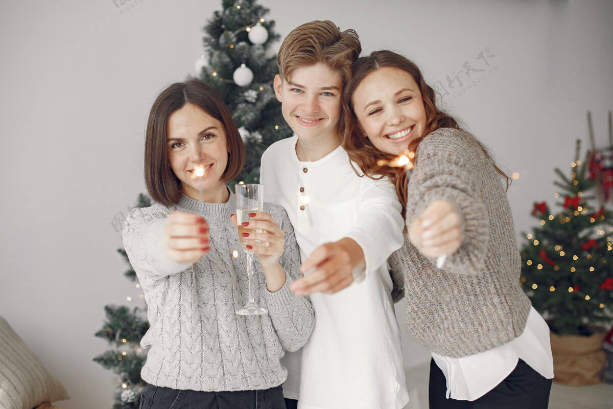 花环人们在为圣诞节做准备母亲和儿子站在一起一家人在节日的房间里休息人们拿着香槟和火花装饰人十二月