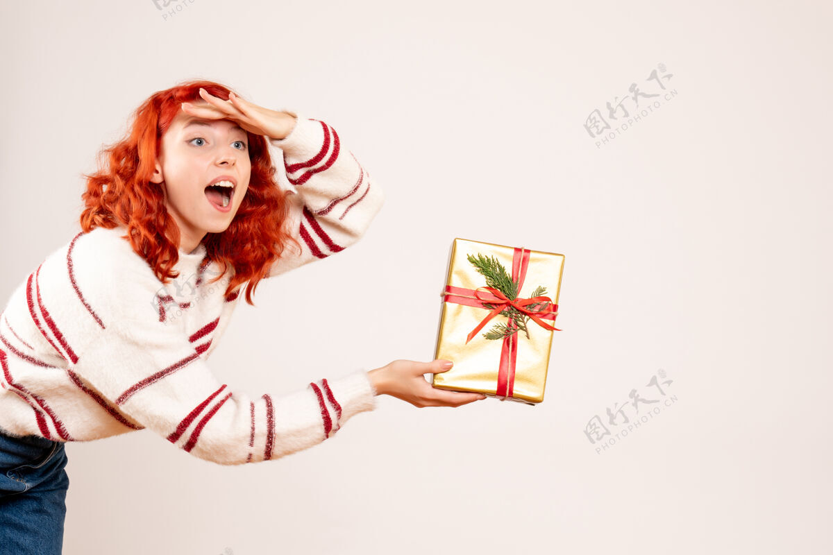 脸白色墙上挂着圣诞礼物的年轻女子的正视图微笑盒子女士