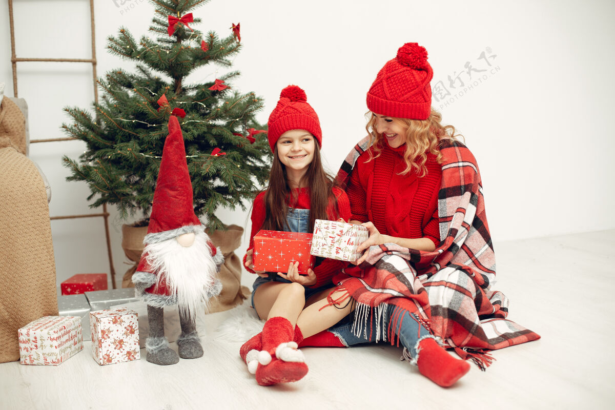 肖像人们在为圣诞节做准备母亲在和女儿玩耍一家人在节日的房间里休息孩子穿着红色毛衣亮光给圣诞节